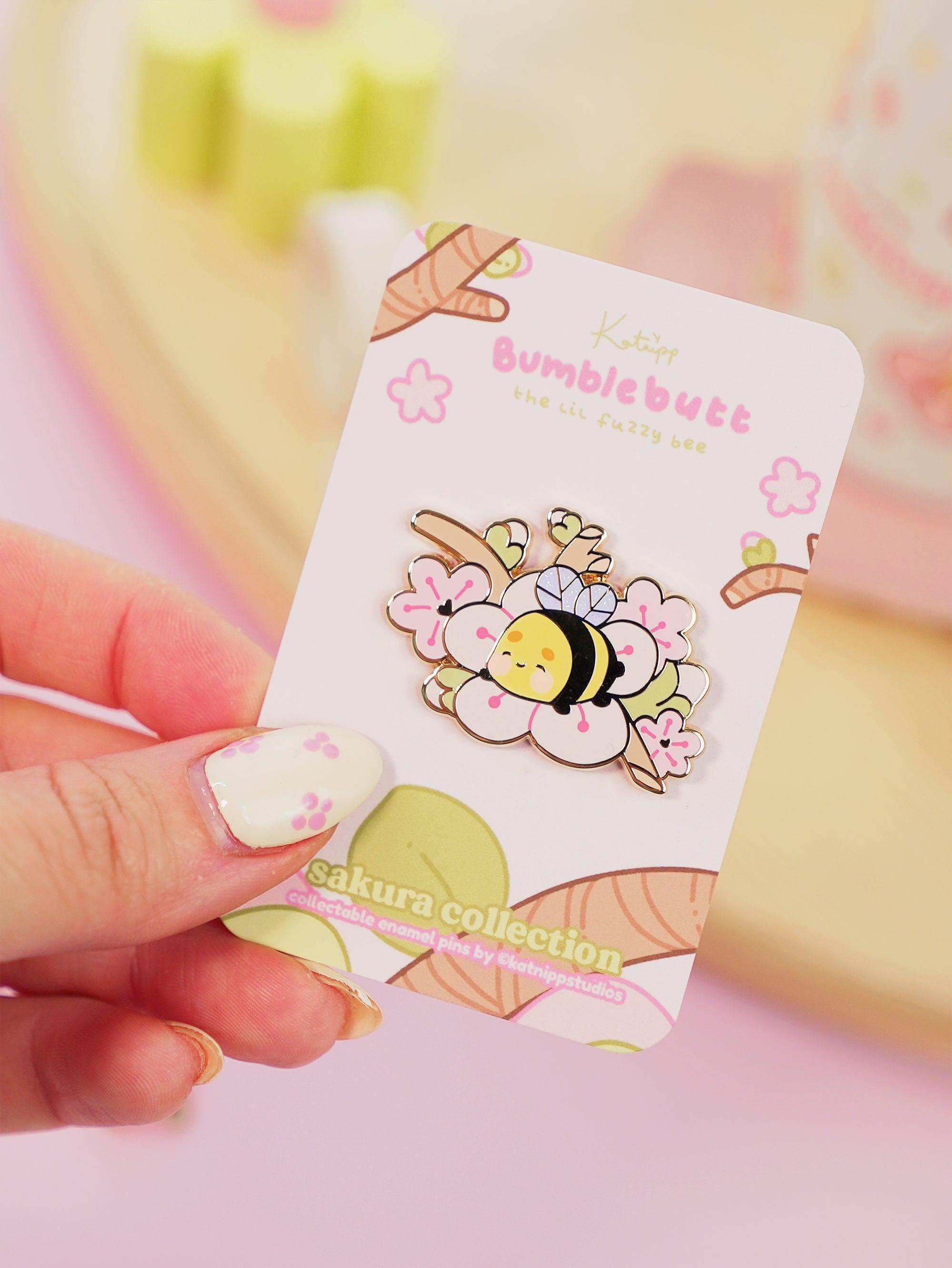 Enamel pin featuring Bumblebutt resting on a blossom branch, part of the Sakura Collection from Katnipp.