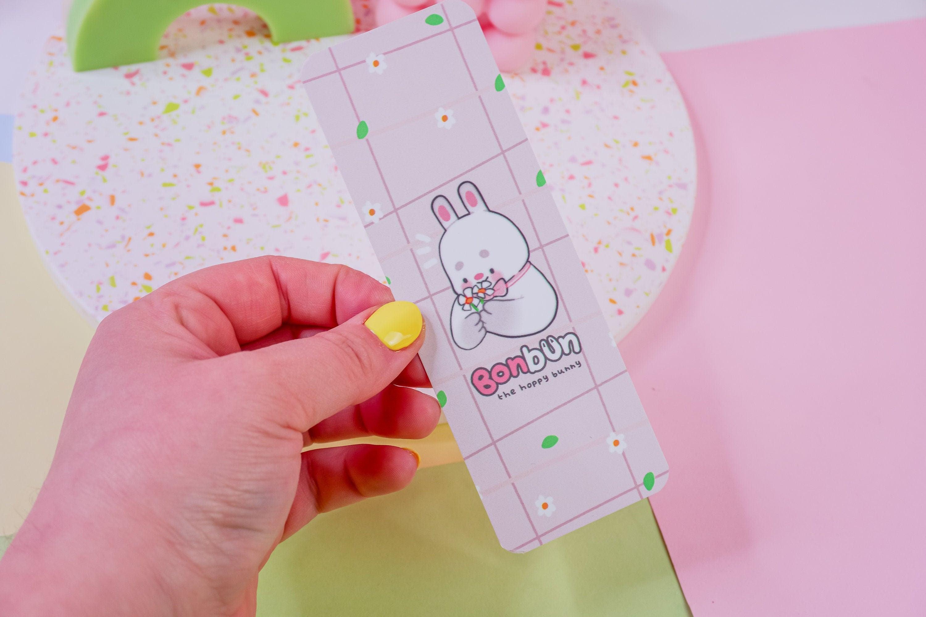 Bonbun the Spring Bunny Bookmark - Featuring Bonbun picking flowers on a charming bookmark printed on quality 400gsm cardstock with smooth velvet lamination.
