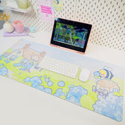 A large gaming mouse pad with a blue hydrangea and bumblebee design, laid out on a desk with a keyboard and mouse.