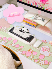 A gaming desk mat with a whimsical spring design, featuring cartoon sheep, tulips, and a cottage, in a large size covering most of the desk.