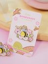 Enamel pin featuring Bumblebutt resting on a blossom branch, part of the Sakura Collection from Katnipp. 9