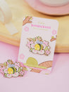 Enamel pin featuring Bumblebutt resting on a blossom branch, part of the Sakura Collection from Katnipp. 11